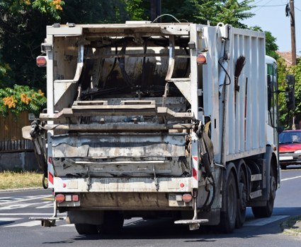 Workers reviewing risk assessment documents near waste containers